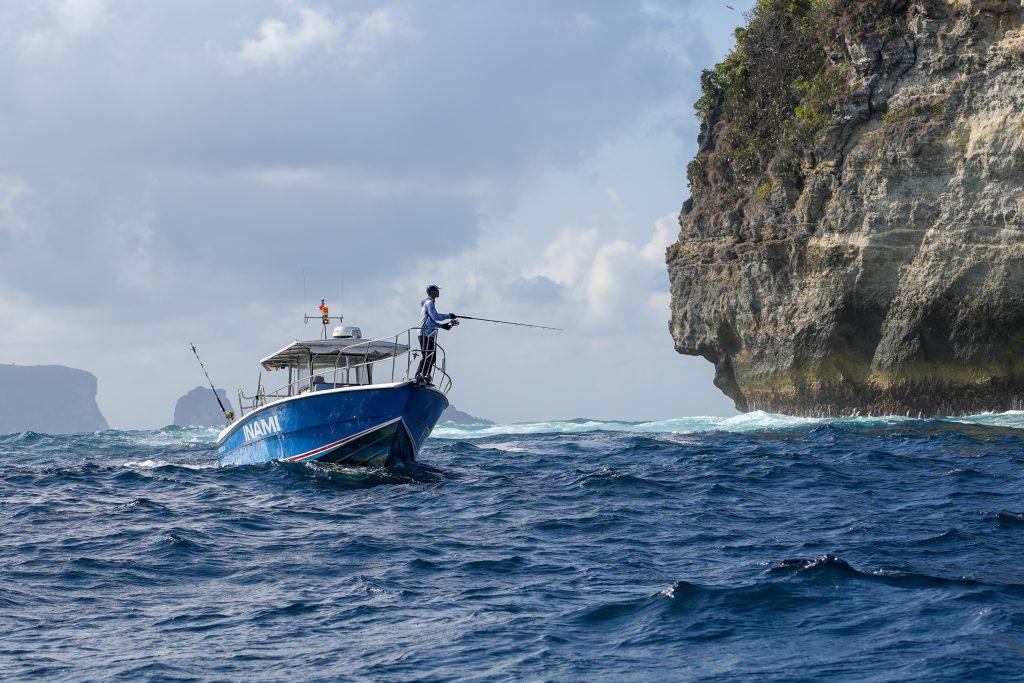 Fishing enthusiast casting a line from the deck of Inami during a Bali fishing charter